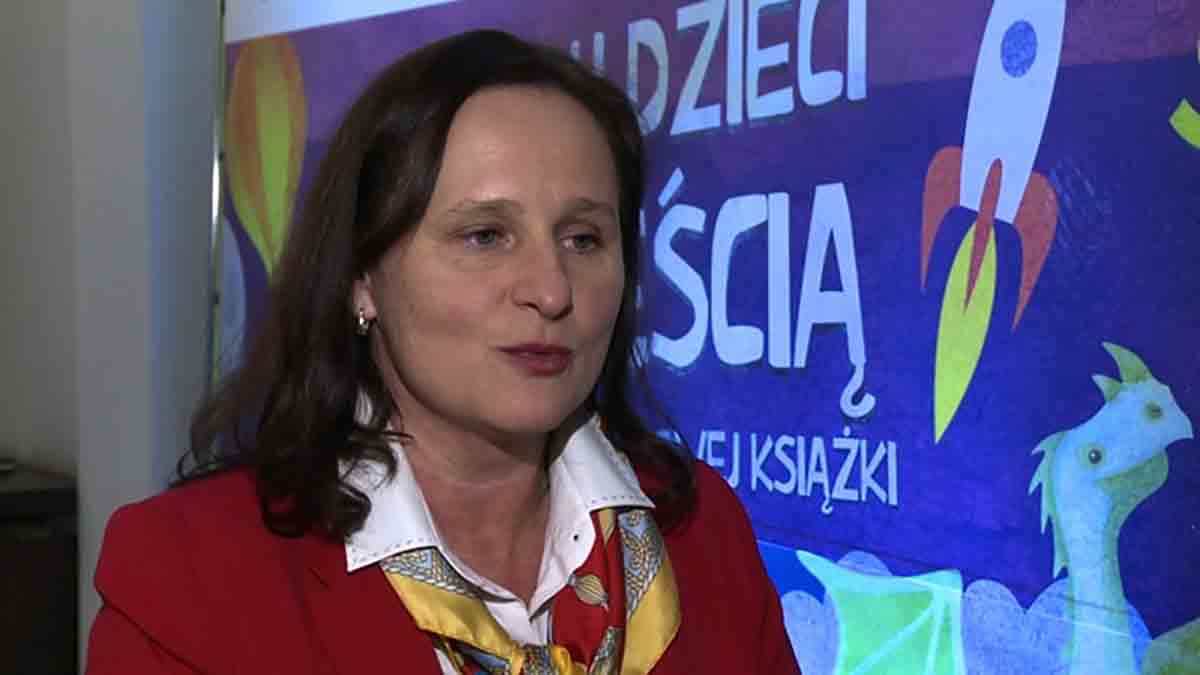 Anetta Jaworska-Rutkowska w czerwonej marynarce, w tle prezentacja