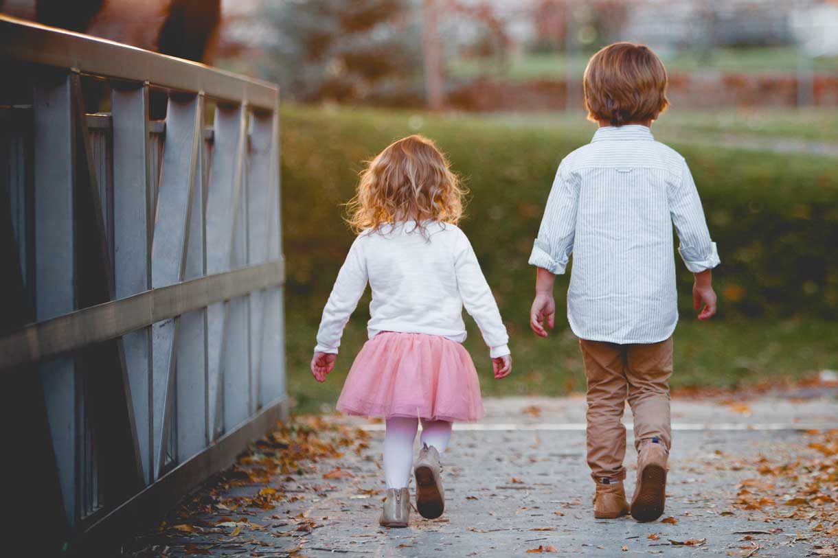 Mała dziewczynka i chłopczyk odchodzą przez mostek.