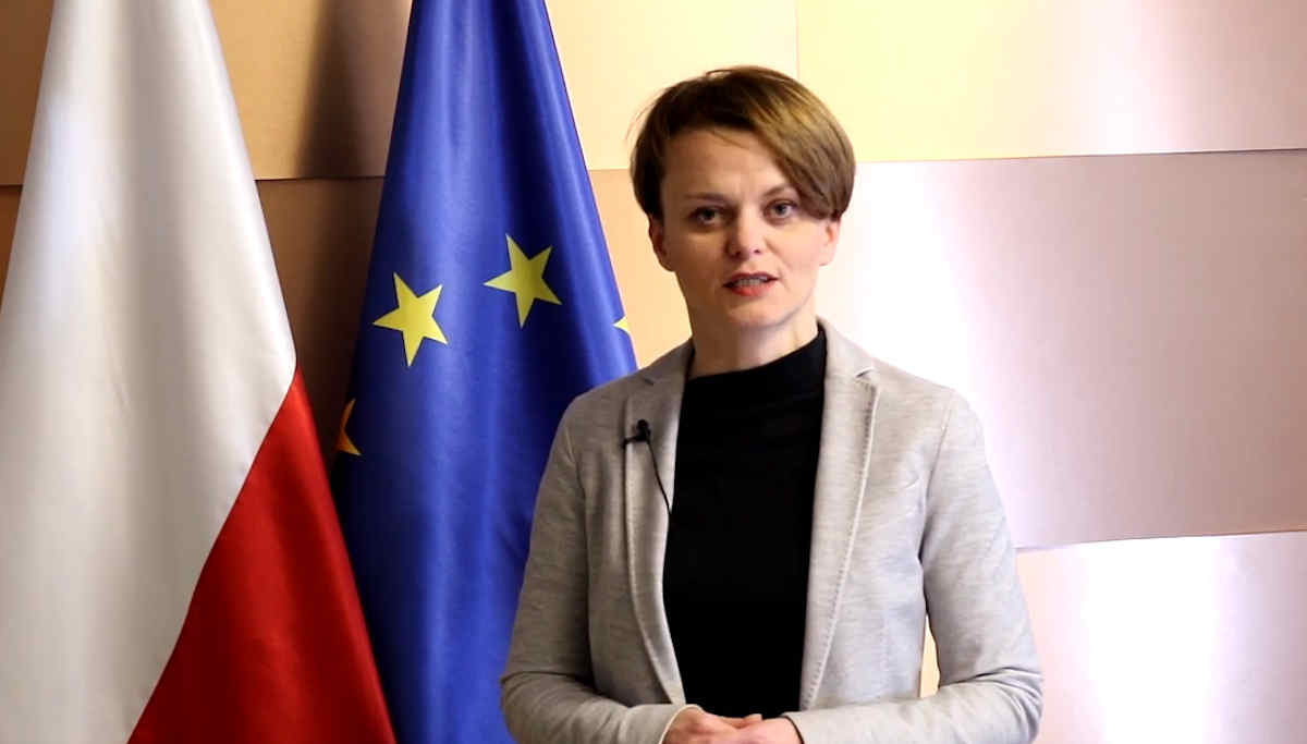 Minister Jadwiga Emilewicz fna tle flagi Polski i UE
