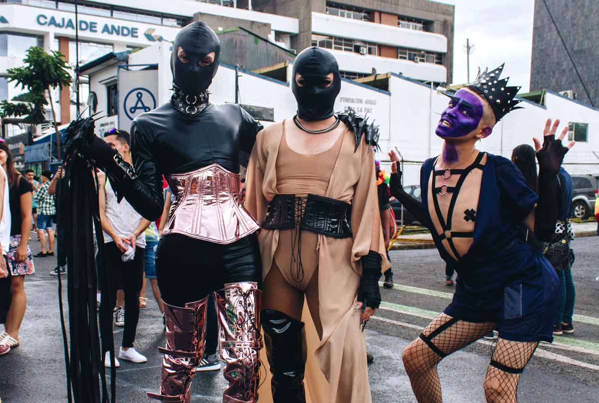 Grupa mężczyzn ubrana w gorsety, skórzane paski, z pejczami w dziwnych pozach na manifestacji LGBT