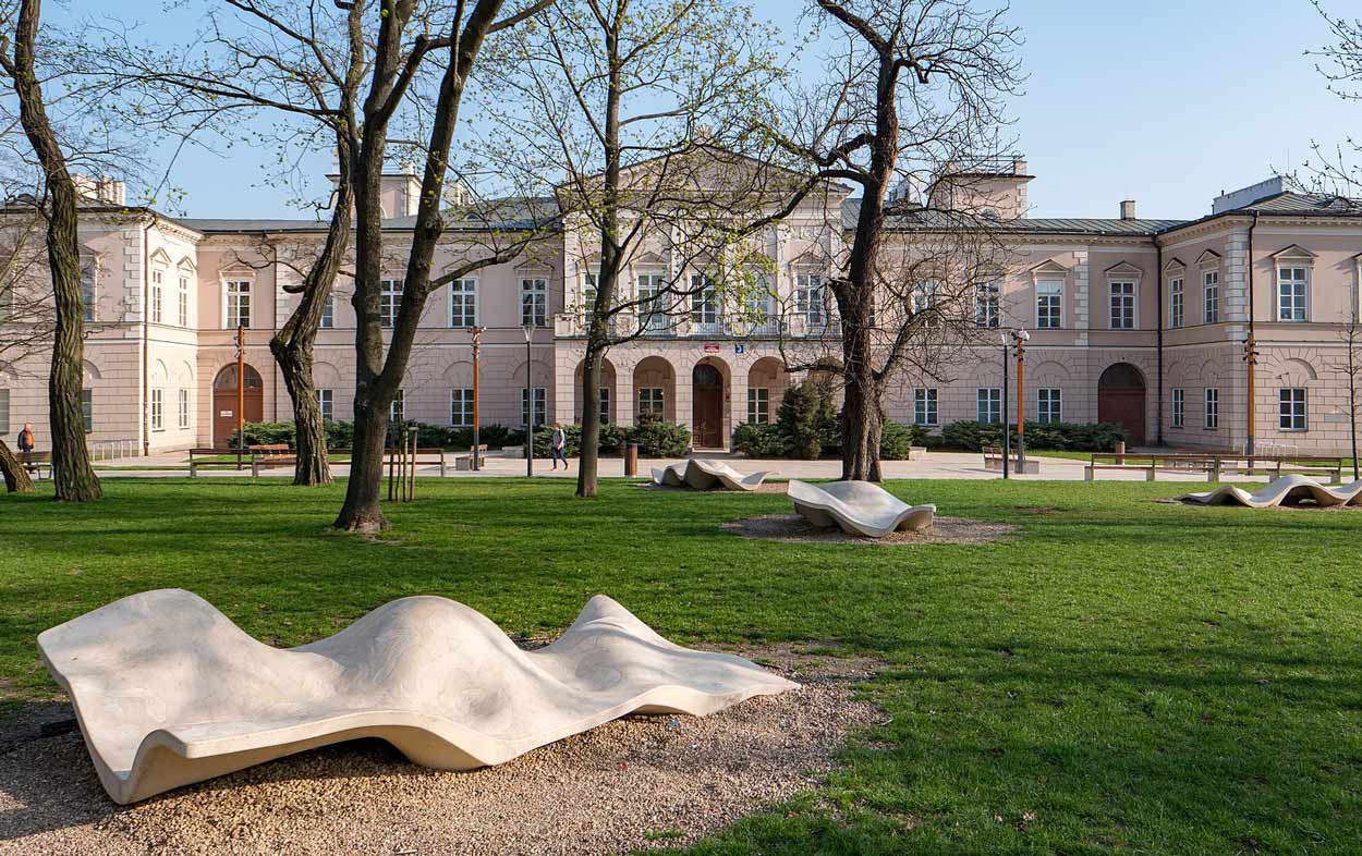 Pałac Lubomirskich w Lublinie, przed nim ekspozycja rzeźb wykonanych z piaskowaca. Przedstawiają pofalowane prostokąty w miękkich kształtach
