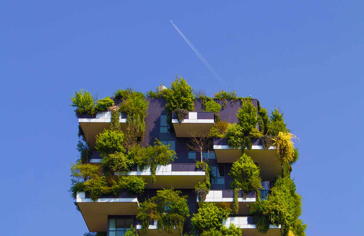 Wielopiętrowy budynek mieszkalny z drzewami i krzewami na każdym balkonie. 