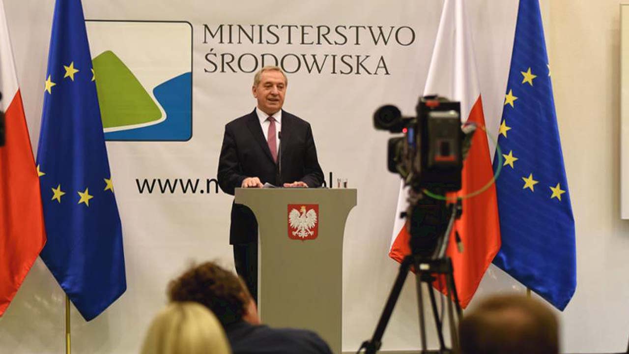 Henryk Kowalczyk przemawia na tle flag Polski i UE